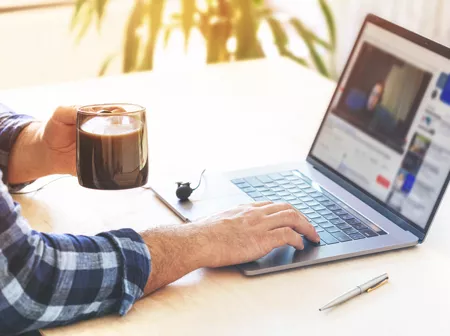 Man drinking coffee while watching training videos.